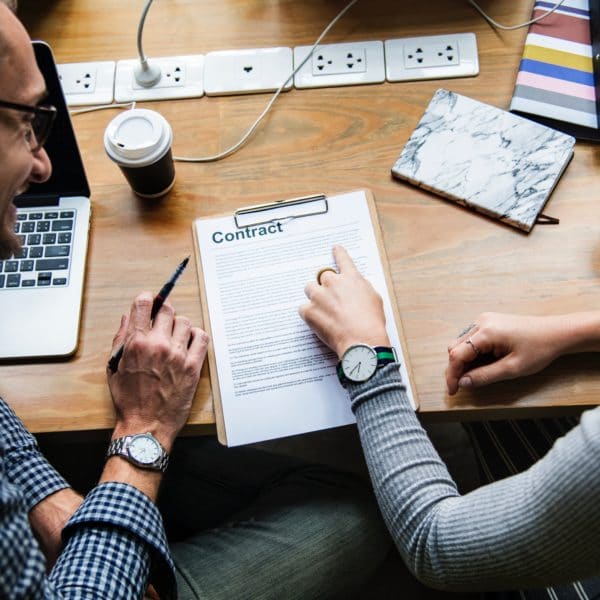 Man and woman reviewing contract at a desk.